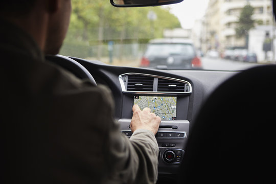 Mid adult man sitting in car, using gps