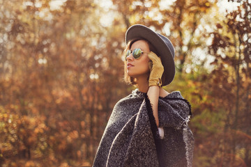 Portrait of a young, elegant woman looking away from the camera. Photogaph taken in autumn surrounding.