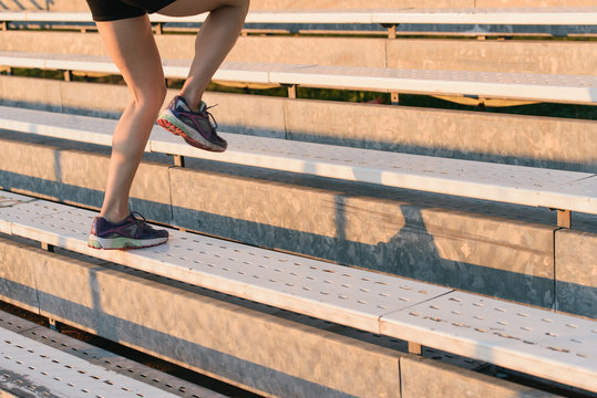 Young woman working out, running up steps, outdoors, low section