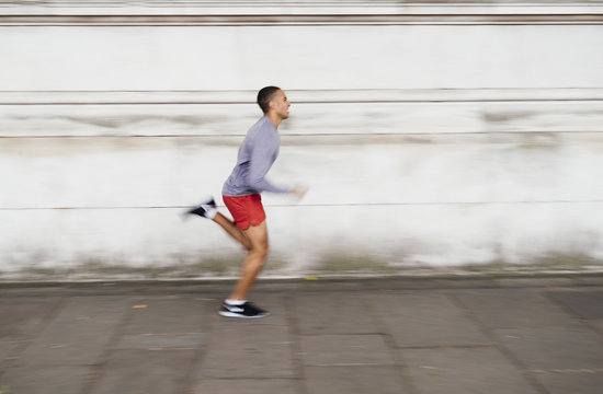 Male runner speeding along sidewalk