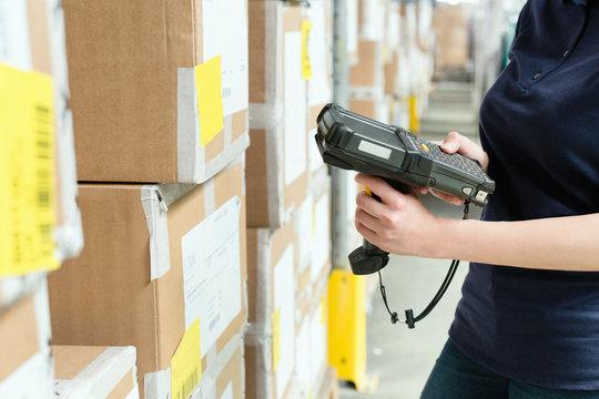 Cropped view of warehouse worker using barcode scanner on box in distribution warehouse