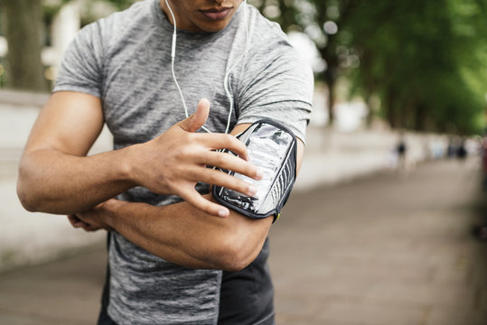 Male runner choosing music on smartphone