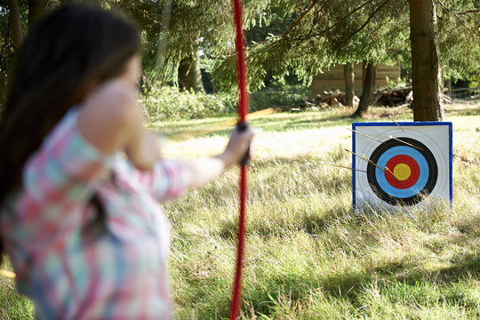 Rear view of teenage girl practicing archery with target
