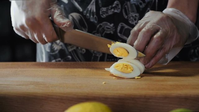 Chef Cuts Boiled Egg by Knife On Board