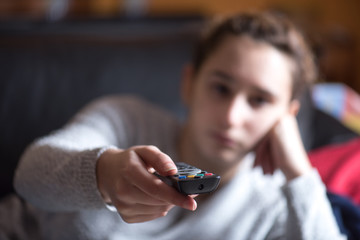 young girl watching TV with remote control