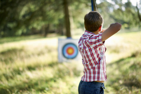 Rear view of teenage boy practicing archery with target