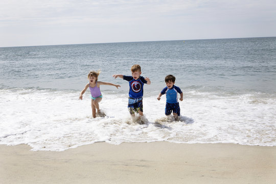 Girl and boys running and slashing in sea