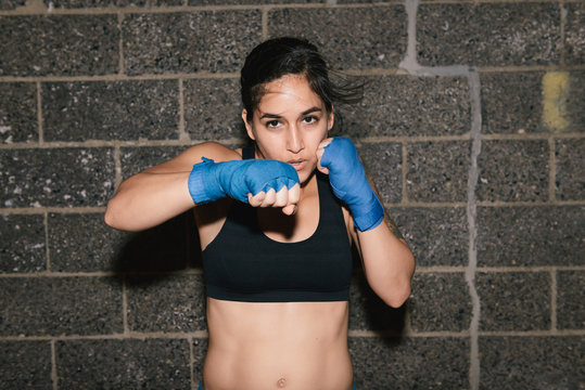A young brunette woman exercising and boxing punching towards the camera