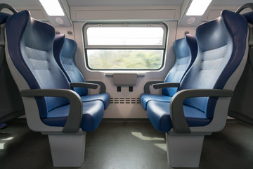 Naklejka premium Four empty blue seats facing each other in modern European train. Railroad trip travel or transportation concept