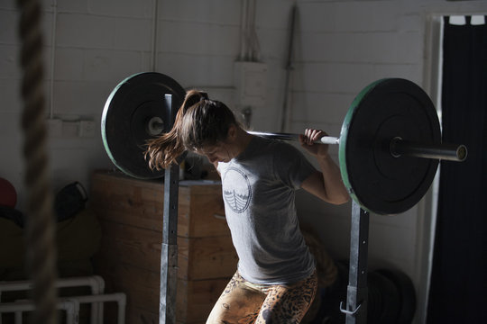Crossfitter lifting barbell in gym