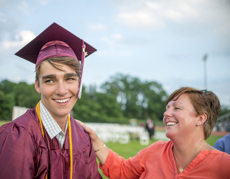 Young man standing with mother at graduation ceremony