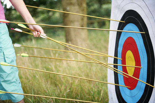 Detail of girl hand retrieving archery arrows from target