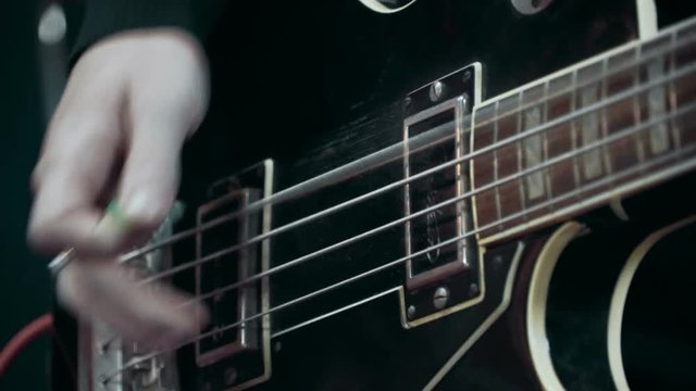 Musician playing bass guitar at studio, close up, slow motion
