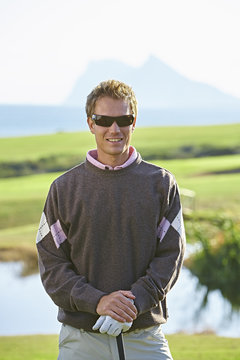 Golfer wearing sunglasses looking at camera smiling