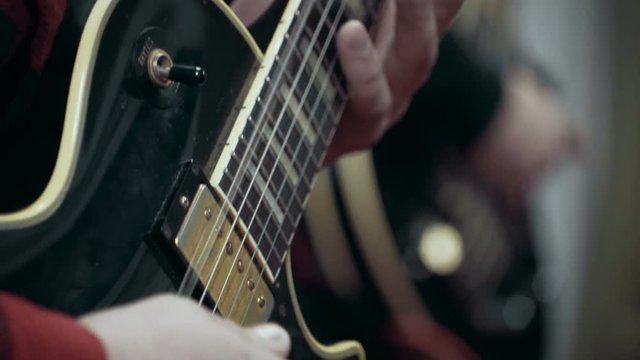 Musician playing electric guitar solo at studio, close up, slow motion