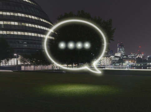 Glowing speech bubble symbol in city at night