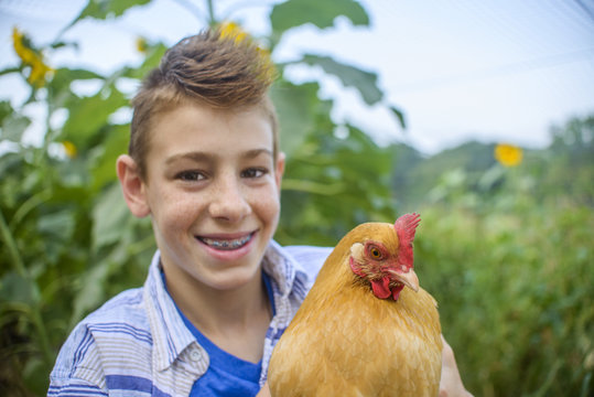 Portrait of boy in field holding hen