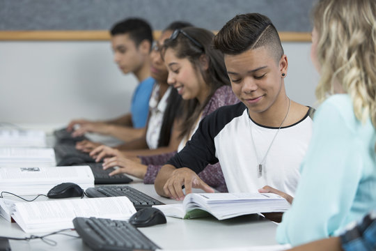 Row of teenage high school students working together in computer class