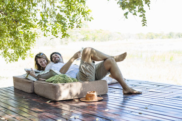 Couple reclining on seats at safari lodge, Kafue National Park, Zambia