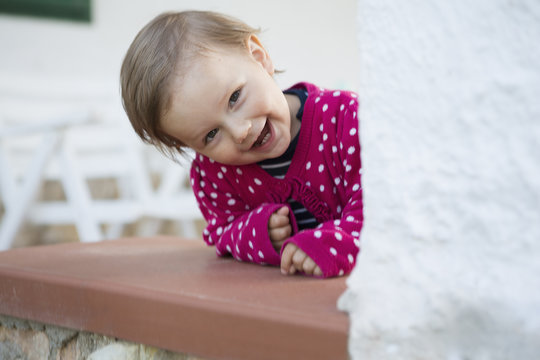 Portrait of female toddler leaning forward and peeking from table