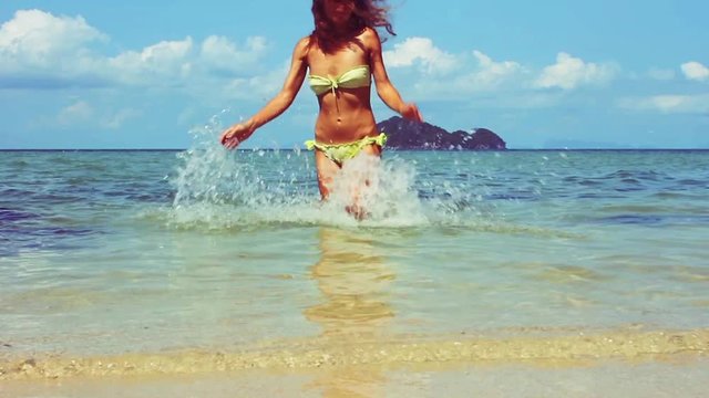 young woman is running out water in bikini enjoying freedom during summer holidays. Beautiful, happy, free girl. slow motion