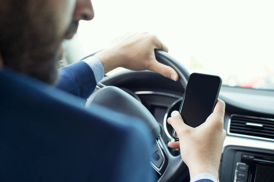 Young businessman reading smartphone text in car