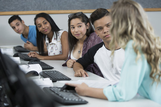 Row of high school students talking in computer class