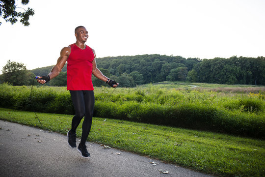 Young man training with skipping rope on path