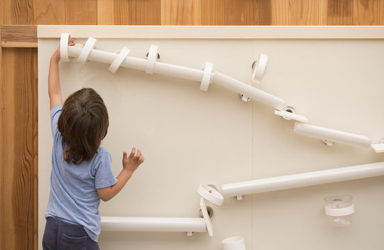 Young boy playing with tumbling puzzle, rear view