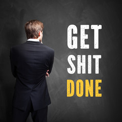 Manager steht vor Wand mit Slogan 