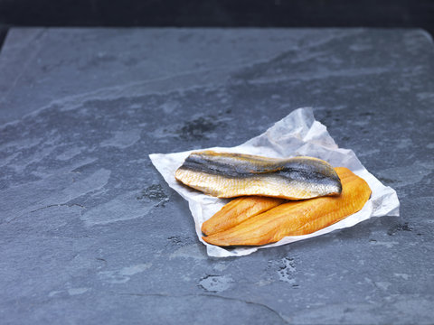 High angle view of raw Scottish kipper fillets on baking paper and slate