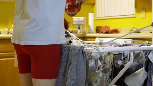 Man standing in his kitchen hanging clothes out of the washer to air dry.