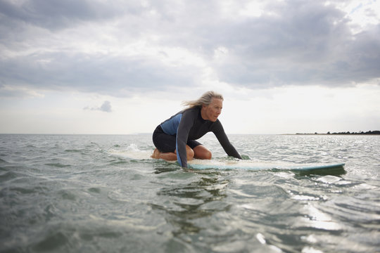 Senior woman on surfboard in sea, paddle boarding