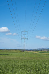 High voltage transmission tower and cable line in the countryside under a blue sky