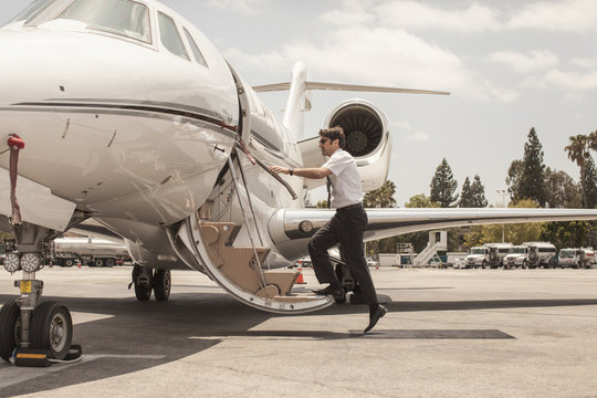 Male private jet pilot boarding plane at airport