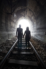 Couple walking together through a railway tunnel