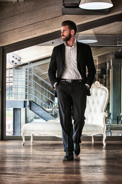 Full length front view of mid adult man wearing suit hands in pockets looking away