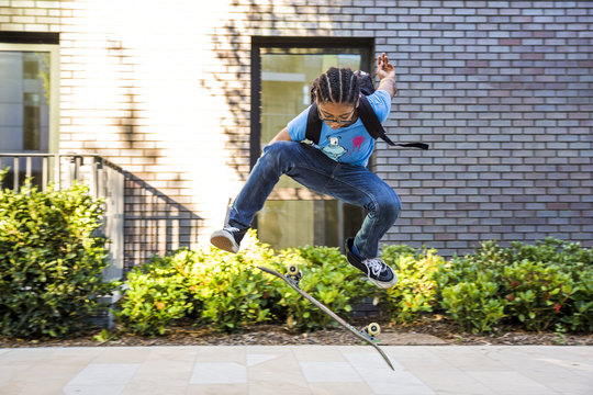 Boy doing skateboarding trick jump on urban sidewalk