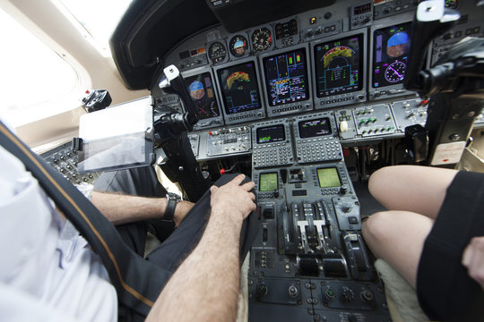 Cropped shot of male and female pilots knees in cockpit of private jet