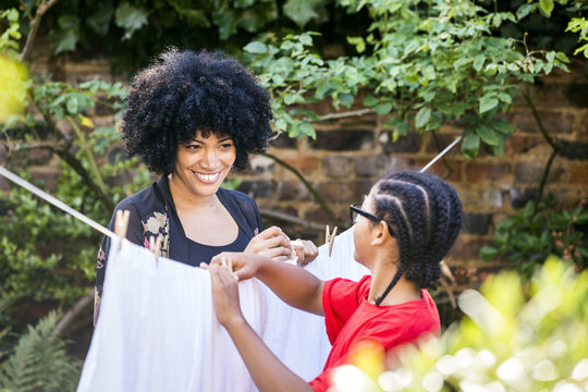 Mature woman and son pegging sheets on garden clothesline