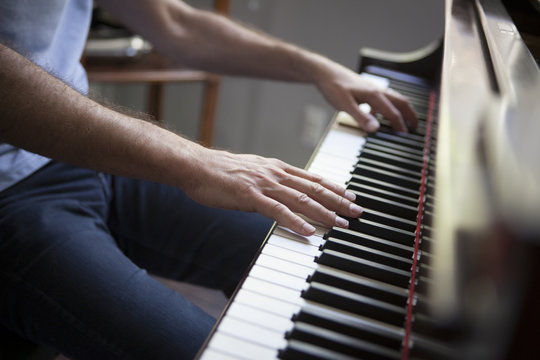 Cropped view of mature man sitting playing piano