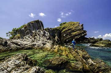 a man enjoy taking photo the beautiful nature seascape of  Kapas Island, Malaysia. Clear  sea water surrounded rocky island with blue sky background at sunny day.