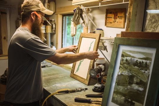 Artist working in workshop, framing artwork