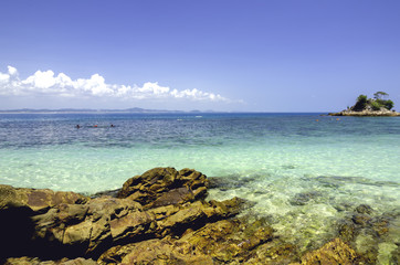 Fototapeta premium scenic sea view of the Kapas Island at Terengganu, Malaysia. Clear sea water and blue sky background. Rocky island and cloudy sky at sunny day.