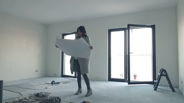 Young woman reading blueprints and checking her new home
