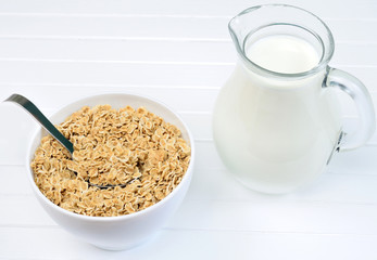 Bowl with oatmeal and milk on table