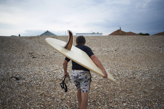 Surfer carrying surfboard on beach
