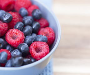 Dessert fresh berries in the bowl. Raspberries and blue-berries on a wooden table. Dessert, fresh berries close-up. 