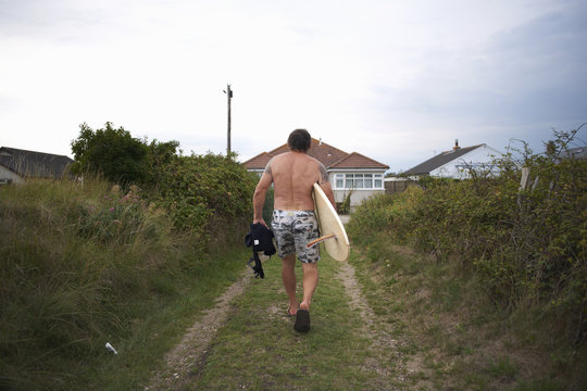 Surfer carrying surfboard home