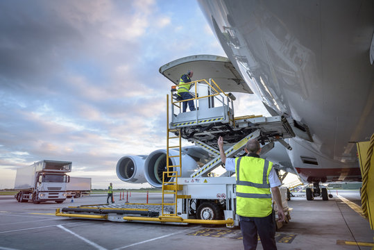 Ground crew attending to A380 aircraft with freight loader at airport